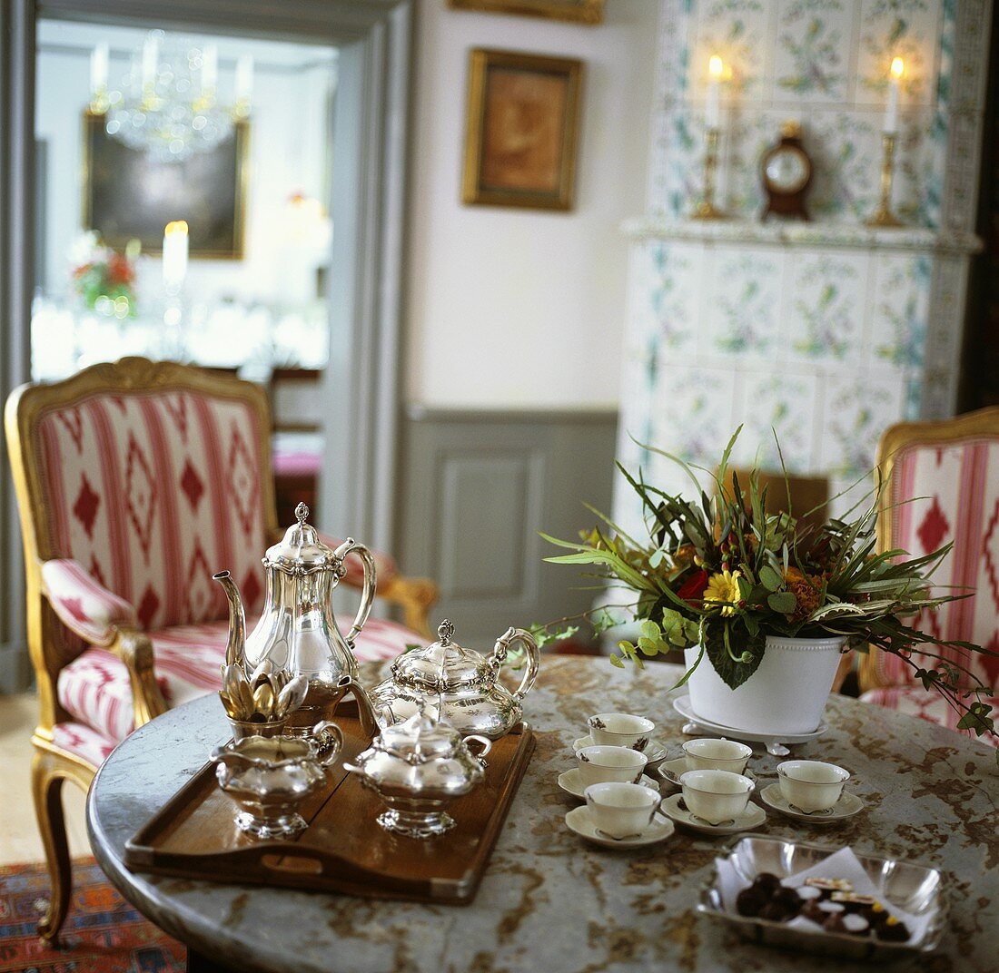 Tray, silver teaset, cups & saucers & chocolates on table