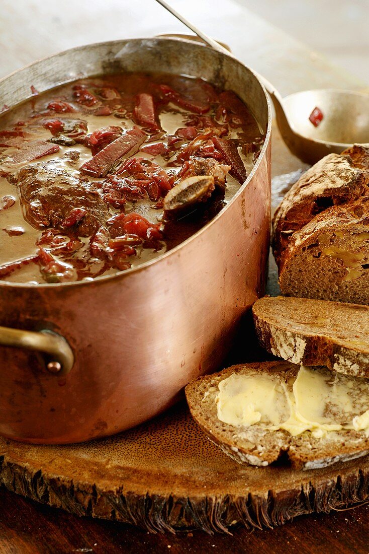 Rote-Bete-Suppe mit Rindfleisch im Kupfertopf, Brotscheiben