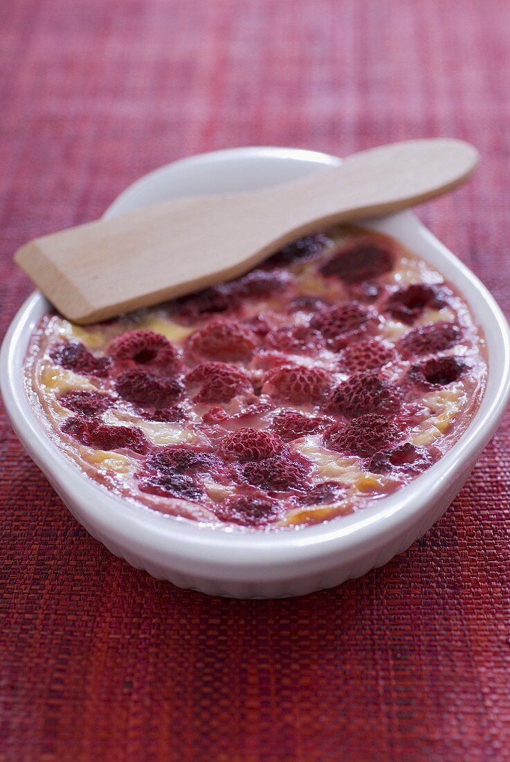 Raspberry gratin in a gratin dish with wooden spatula