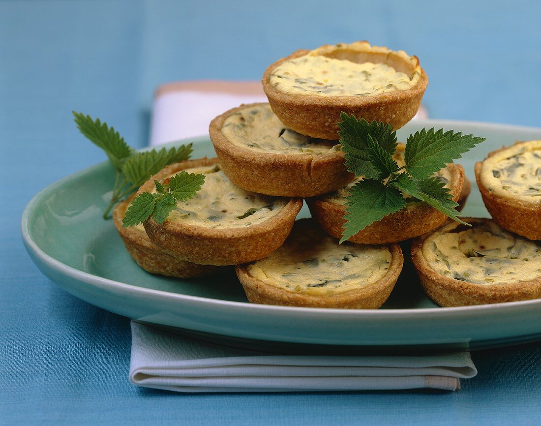 Mini Sauerrahm-Brennnessel-Quiches,gestapelt auf einer Platte