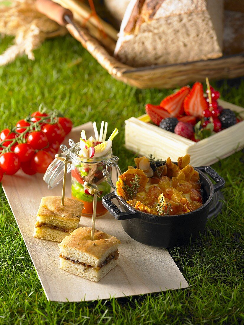 Picknick mit Obst, Gemüse und Häppchen auf Gras im Freien