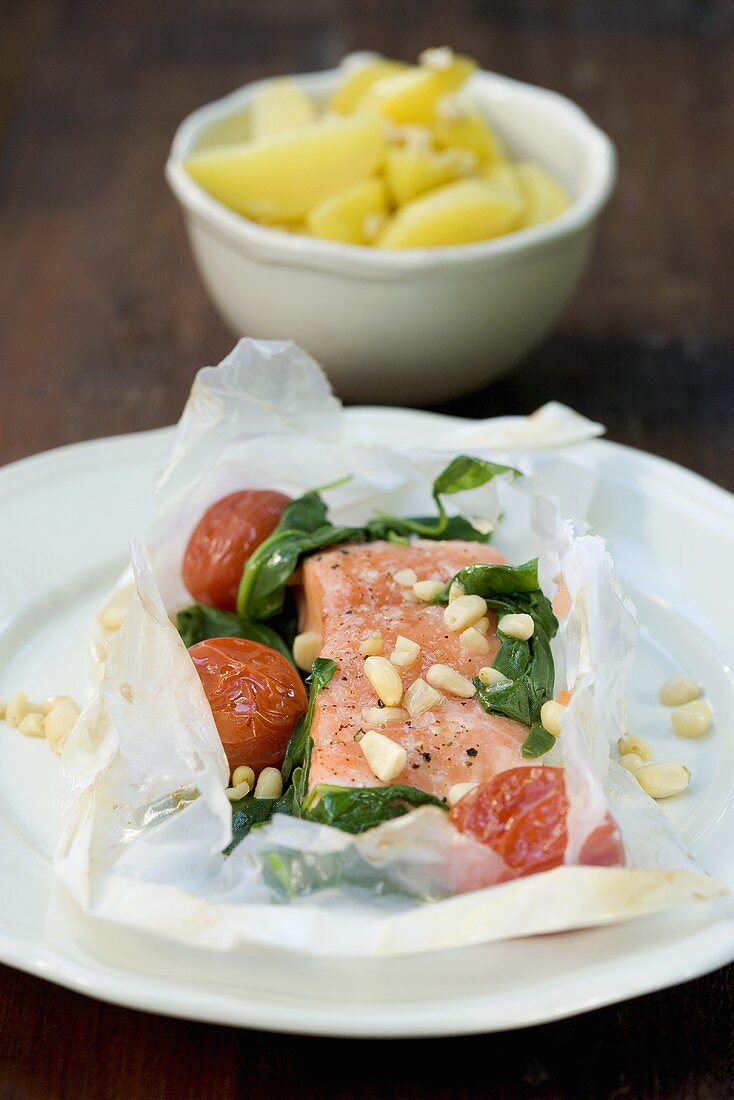 Salmon cooked in paper with garlic, almonds, spinach, tomatoes