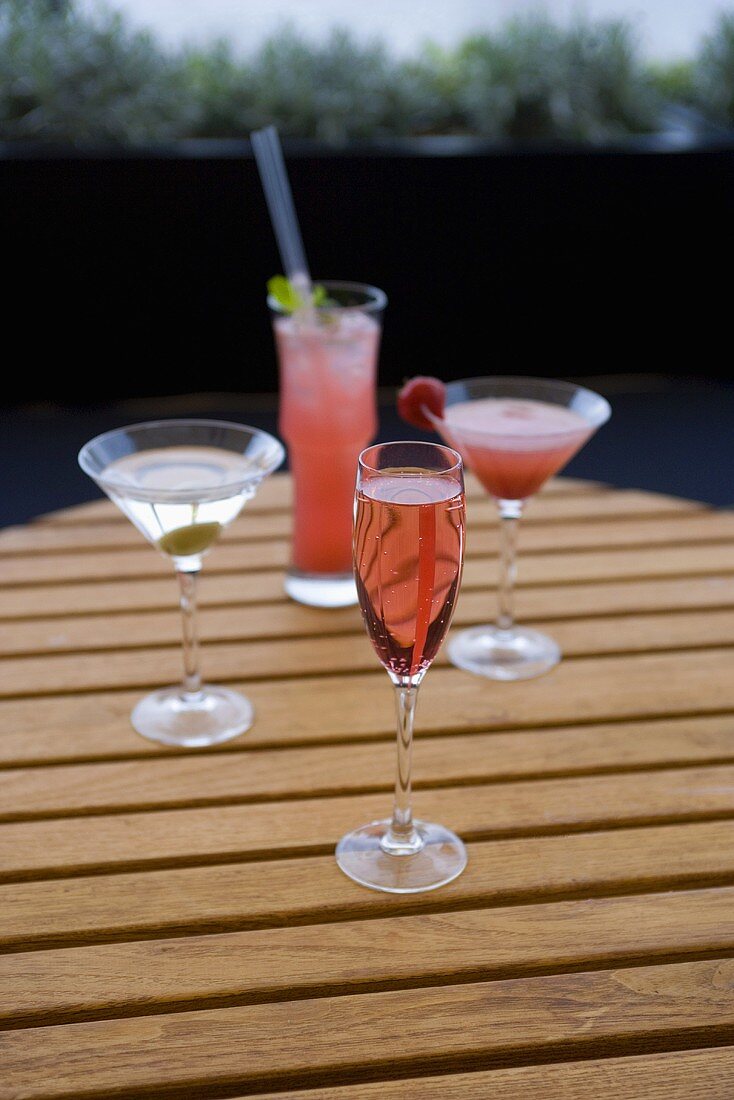 Vier verschiedene Cocktails auf einem Gartentisch
