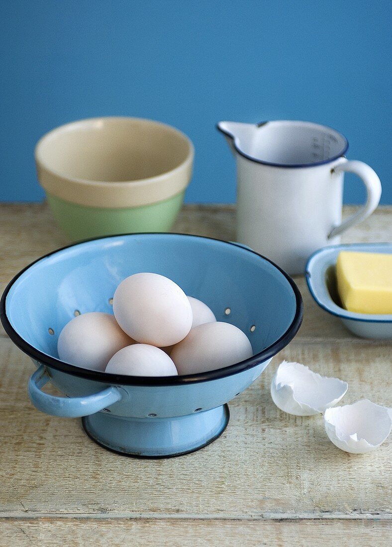 Eier in einem Küchensieb mit Butter und einem Messbecher