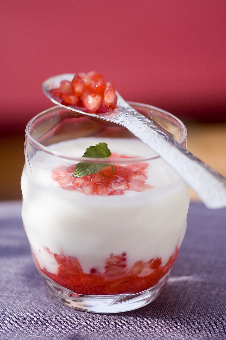 Joghurt mit Granatapfelkernen, Grenadine und Minze im Glas