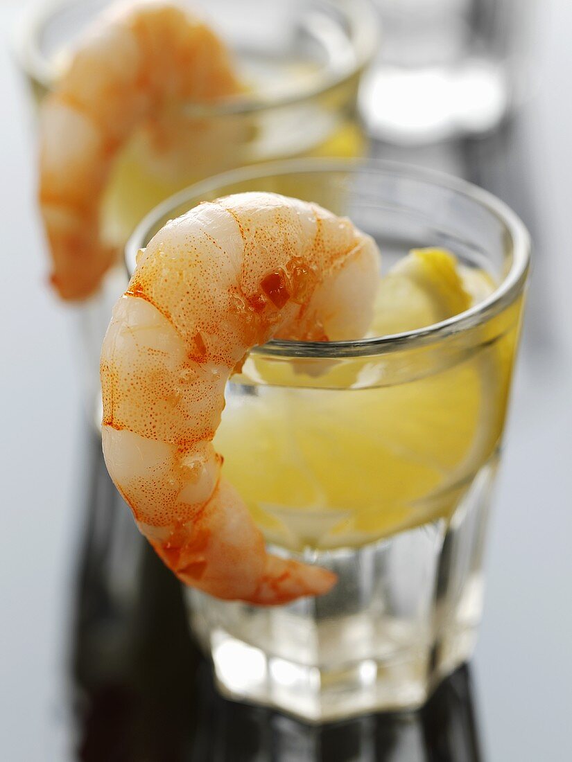 Two glasses of tequila with lemon, prawns on rim