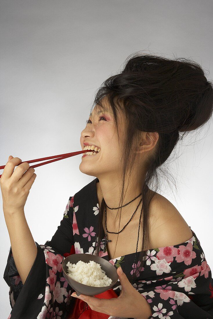 A Japanese woman eating rice and laughing