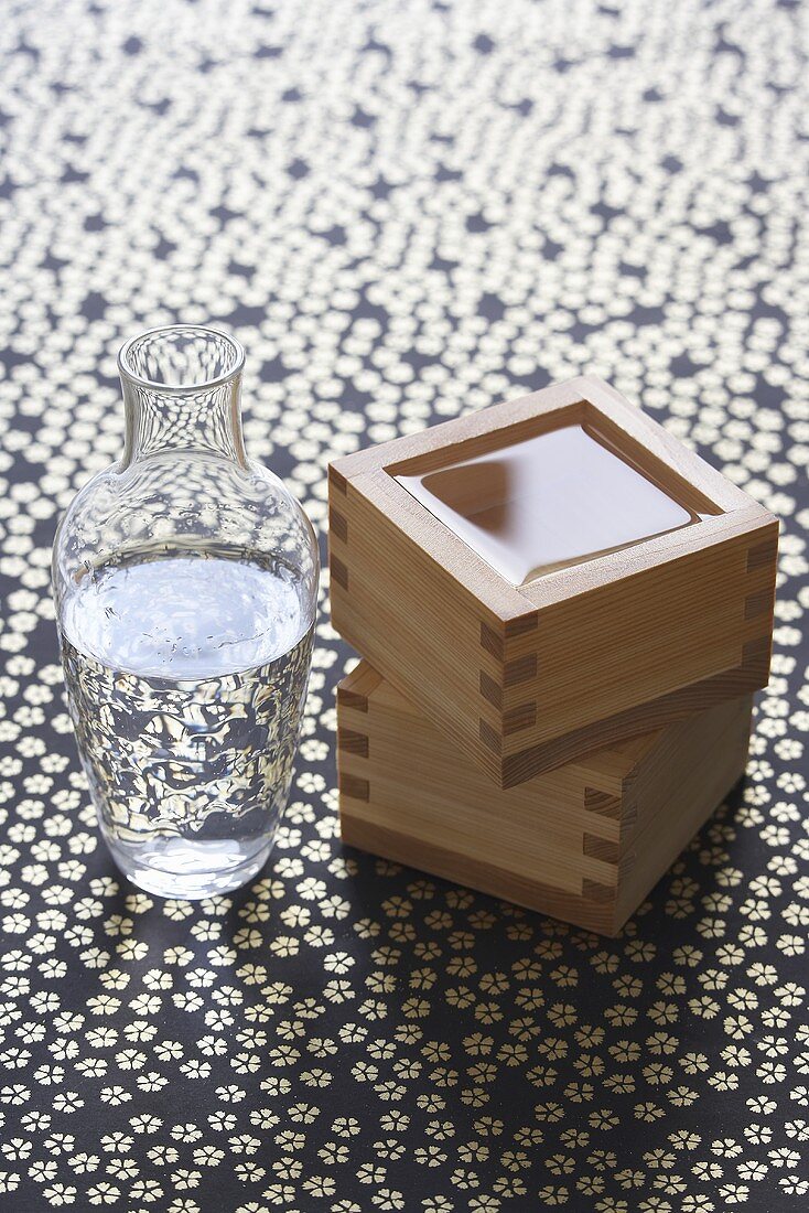 Sake in a glass bottle and two square sake cups