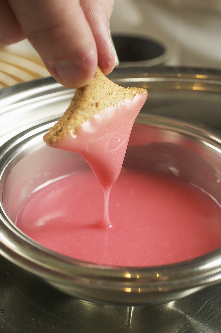 Man dipping wholemeal biscuit in pink icing