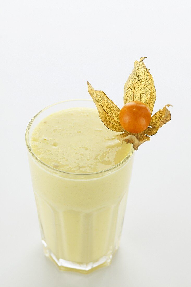 A glass of mango banana shake with a physalis
