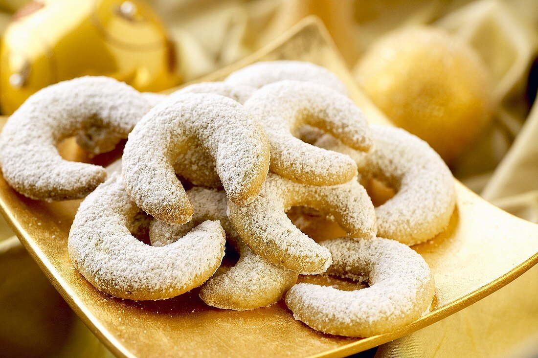Vanilla crescents sprinkled with icing sugar on gold plate