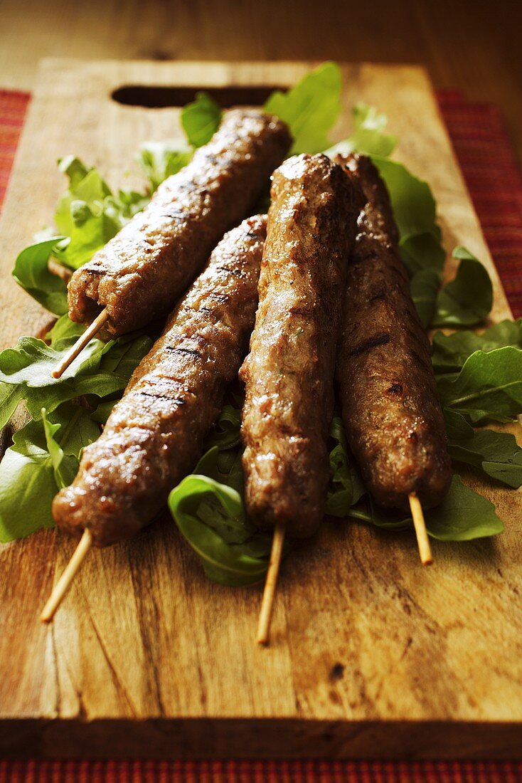 Grilled kebabs with rocket on a wooden board