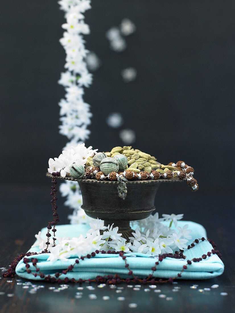 Kardamomkapseln in einer Schale mit Blütendeko
