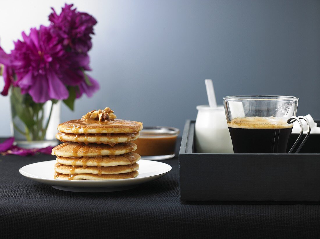 Pancakes mit Ahornsirup und Kaffee auf einem Tablett