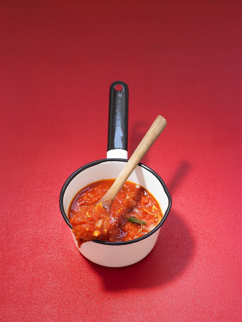 Tomato sauce in a small pan with a wooden spoon