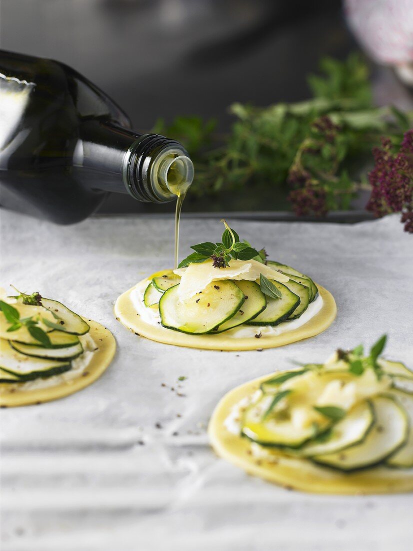 Drizzling courgette puff pastry tarts with olive oil