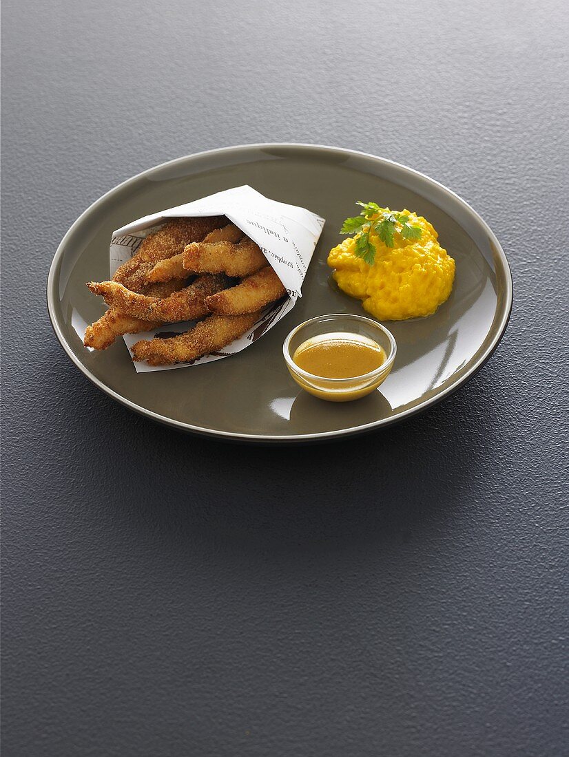 Breaded chicken strips with carrot puree and mustard sauce
