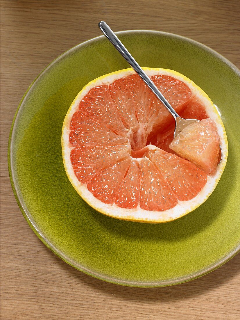 Eine halbe Grapefruit mit einem Löffel
