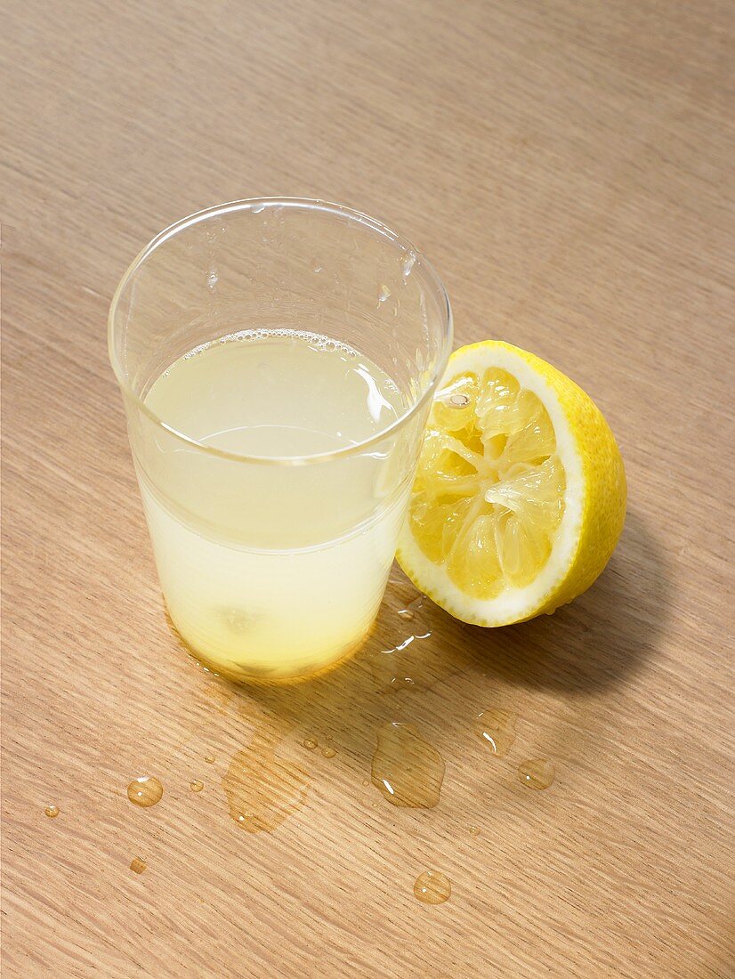 A glass of lemonade with freshly squeezed lemon half