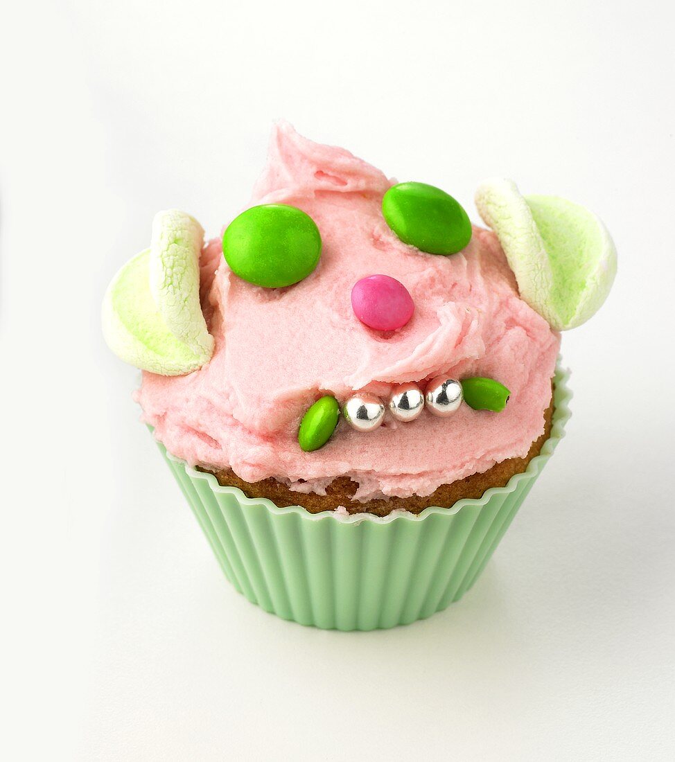 Cupcake with buttercream and amusing face made from sweets