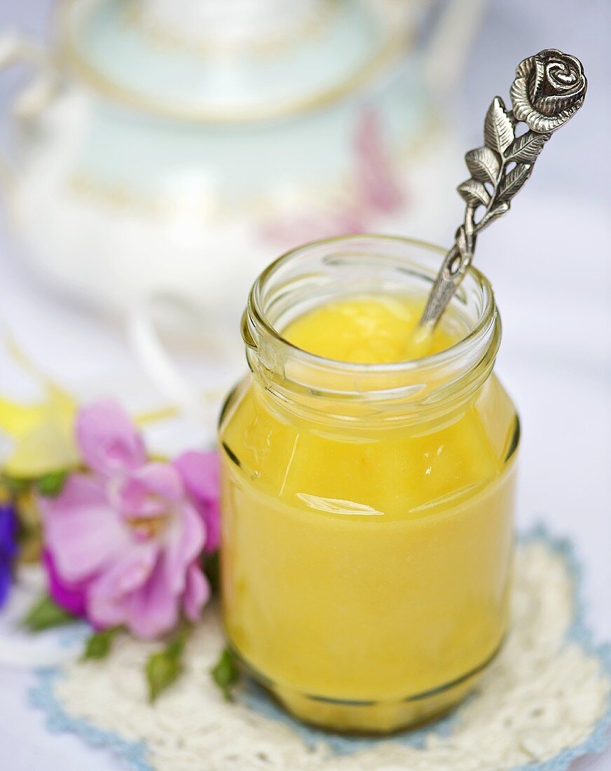 Ein Glas Lemon-Curd mit einem Löffel