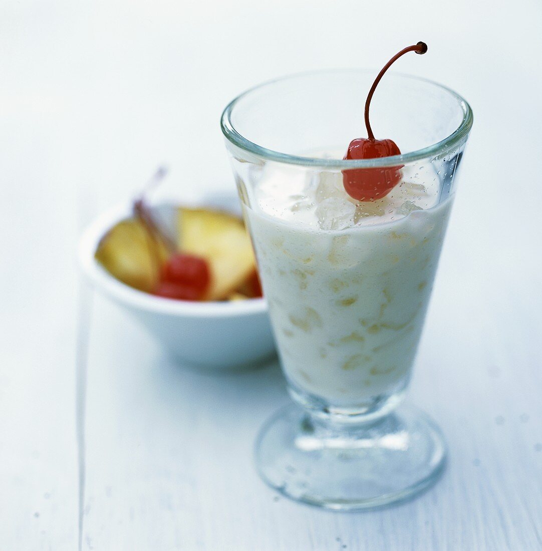 Pineapple and coconut cocktail on ice with cocktail cherry