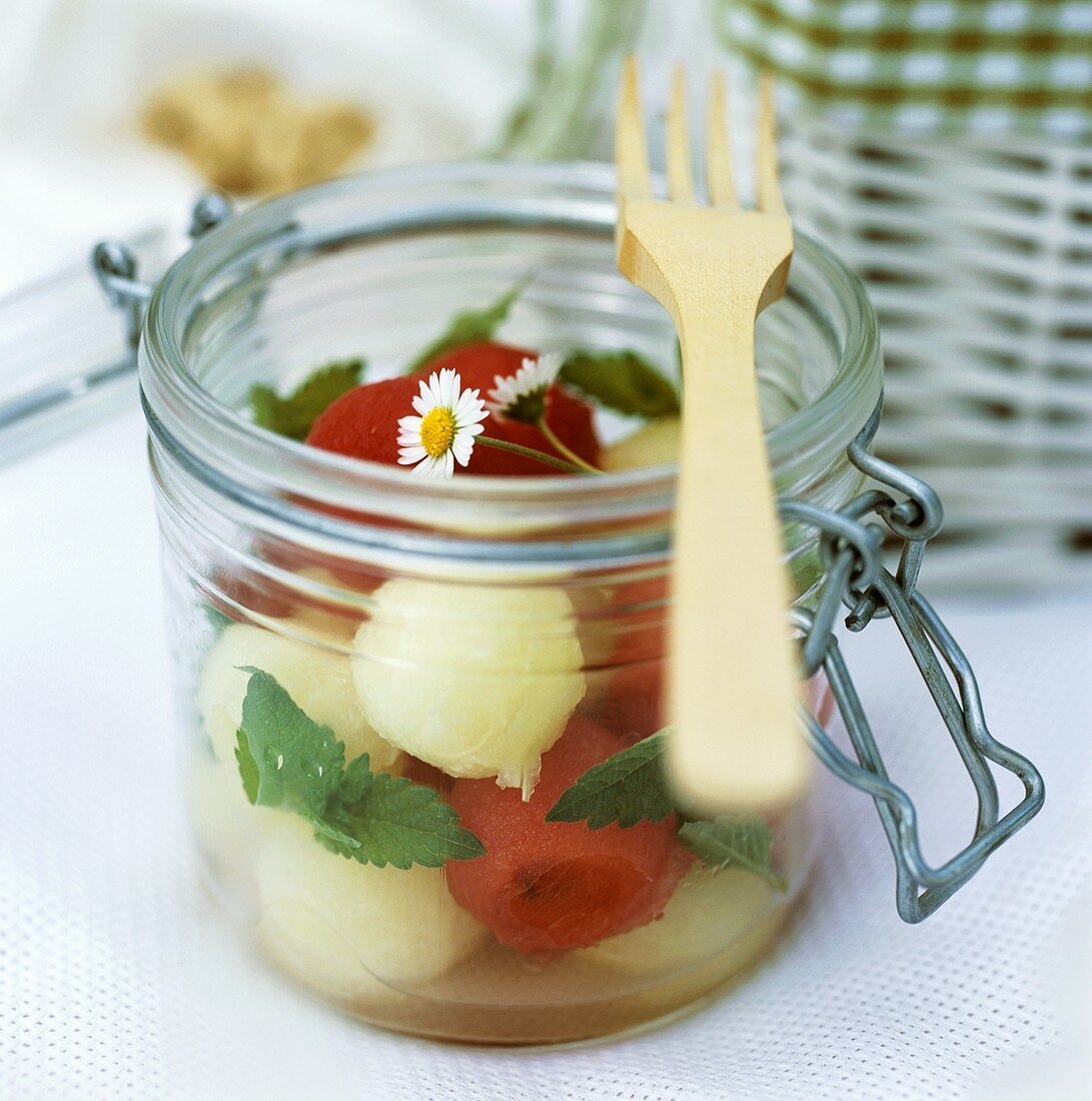 Melon salad with mint and daisies in preserving jar