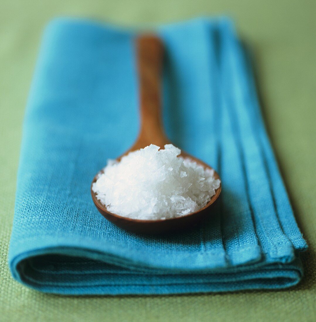 Sea salt on wooden spoon on turquoise napkin