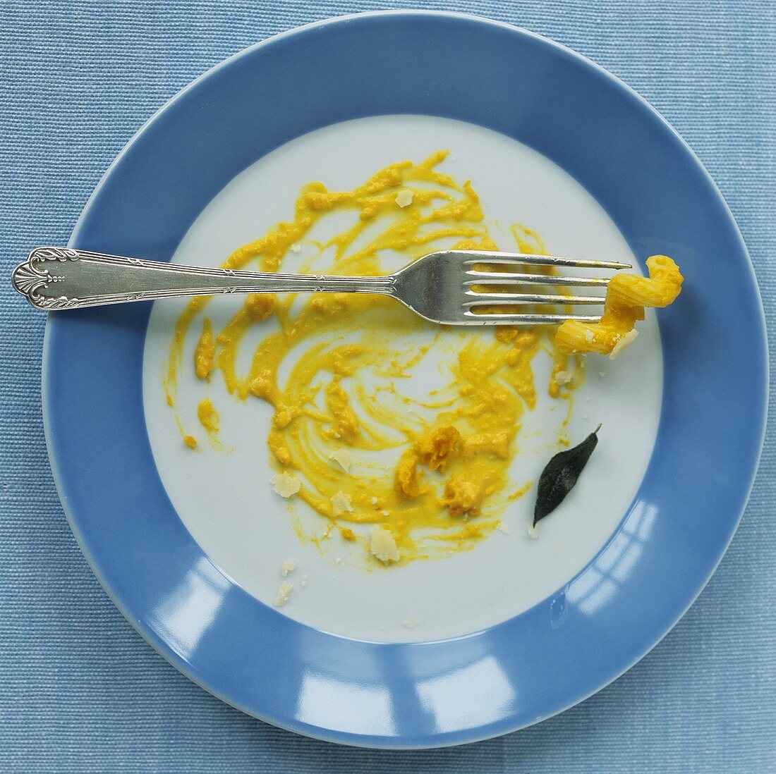 Remains of pasta with pumpkin sauce on a plate with fork