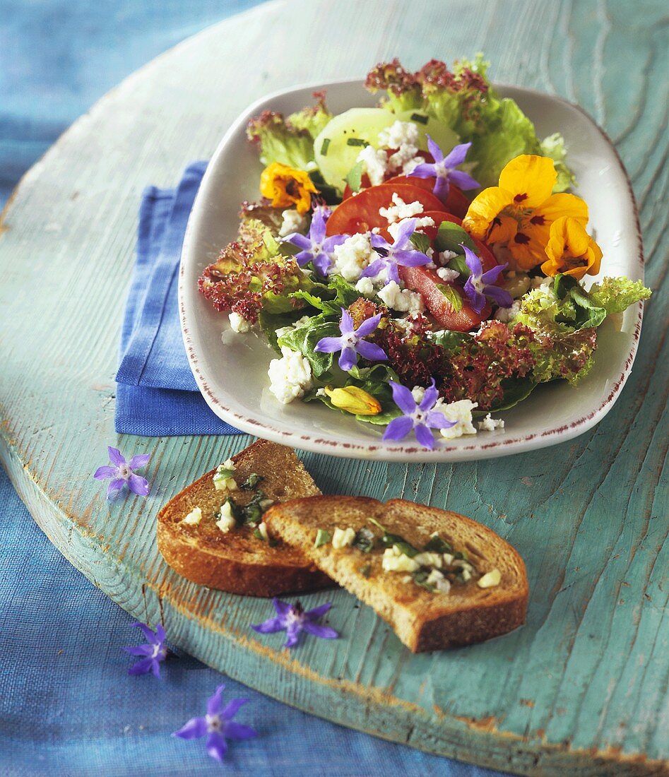 Kräuter-Blattsalat mit Essblüten, Schafskäse, Knoblauch-Brot