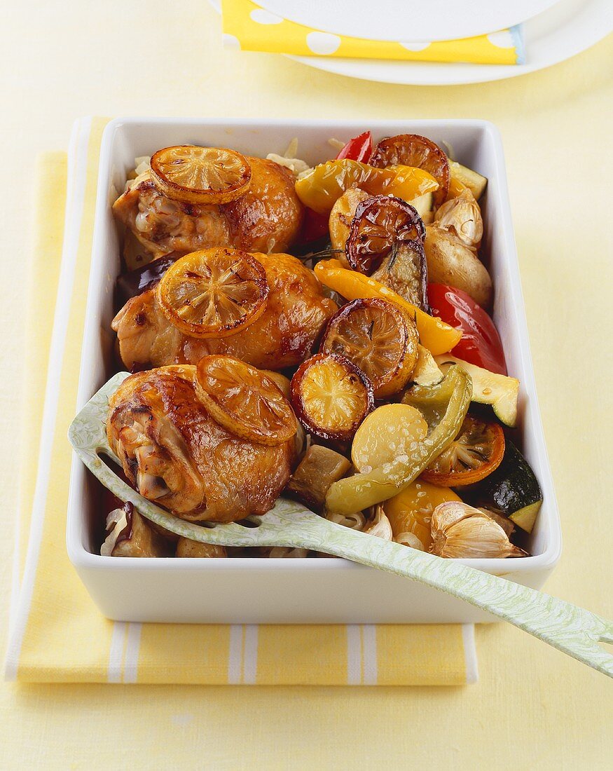 Chicken legs with lemon and vegetables in a baking dish