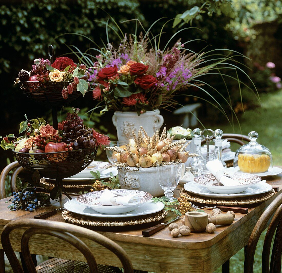 Sommerlich gedeckter Tisch mit Blumen und Früchten im Freien
