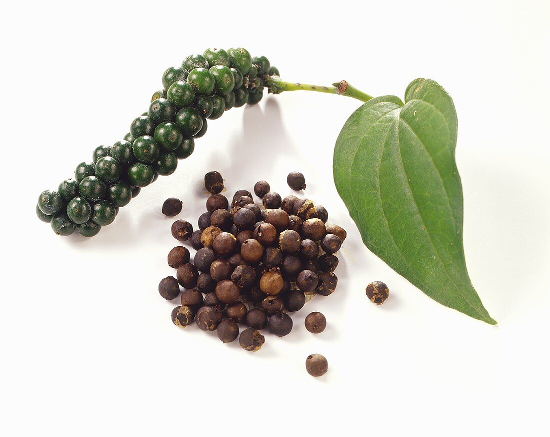Bunch of green peppercorns with leaf and loose peppercorns
