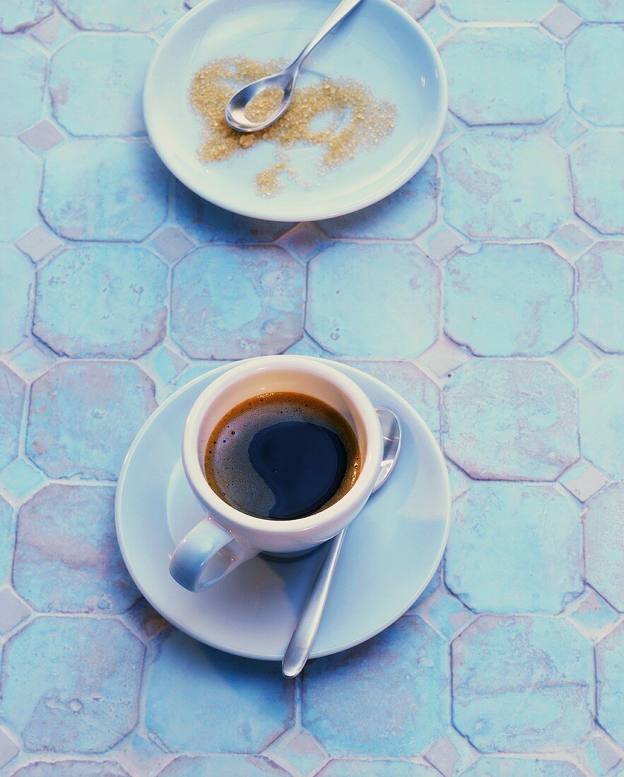 Tasse Espresso und brauner Zucker auf türkisfarbenen Fliesen