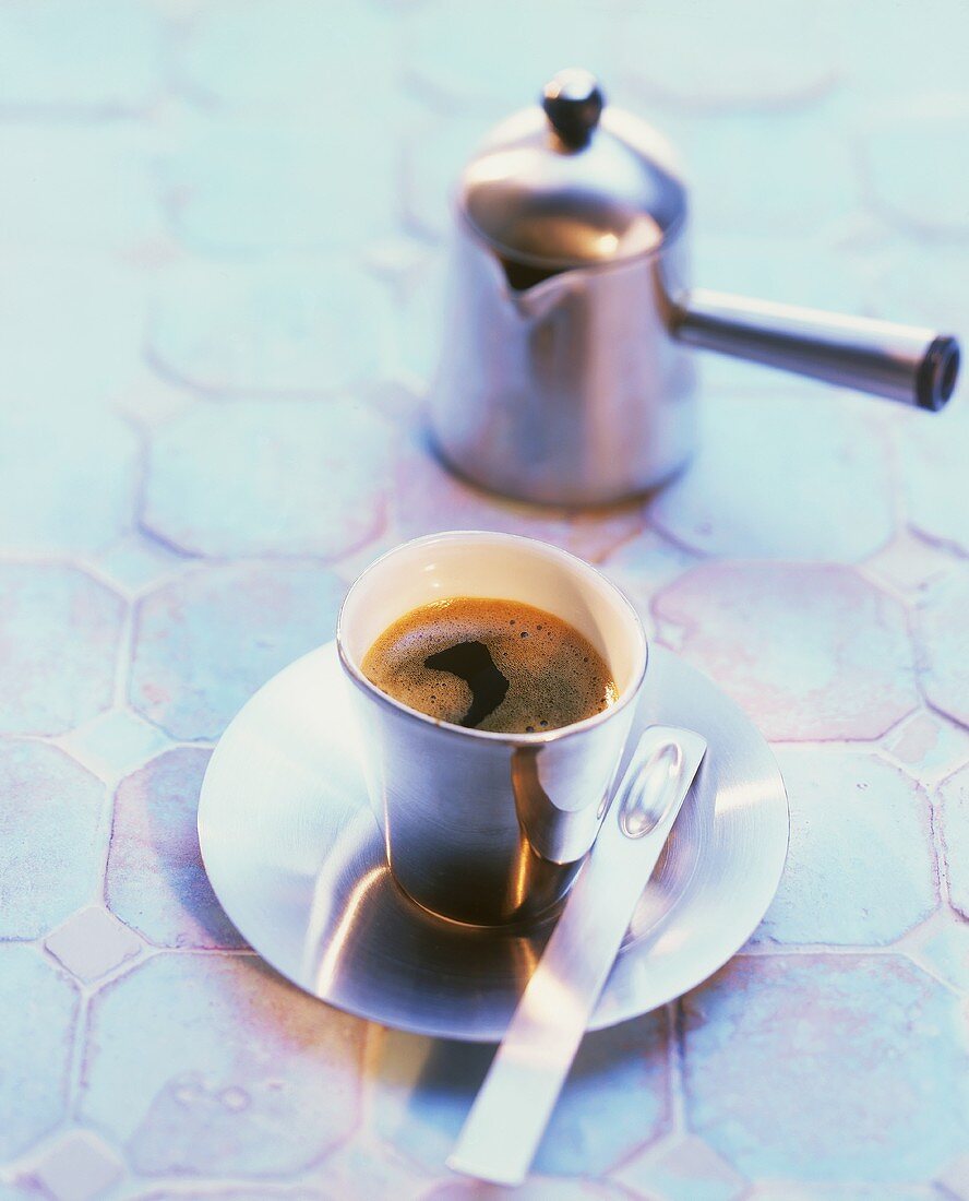 Eine silberfarbene Tasse Espresso mit einem Kännchen