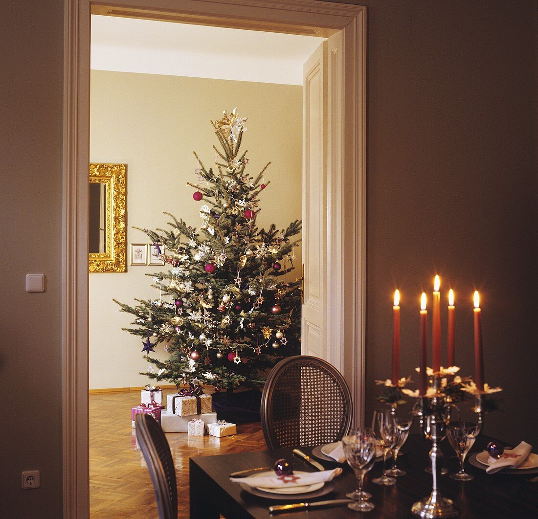 Geschmückter Christbaum, Geschenke, festlich gedeckter Tisch