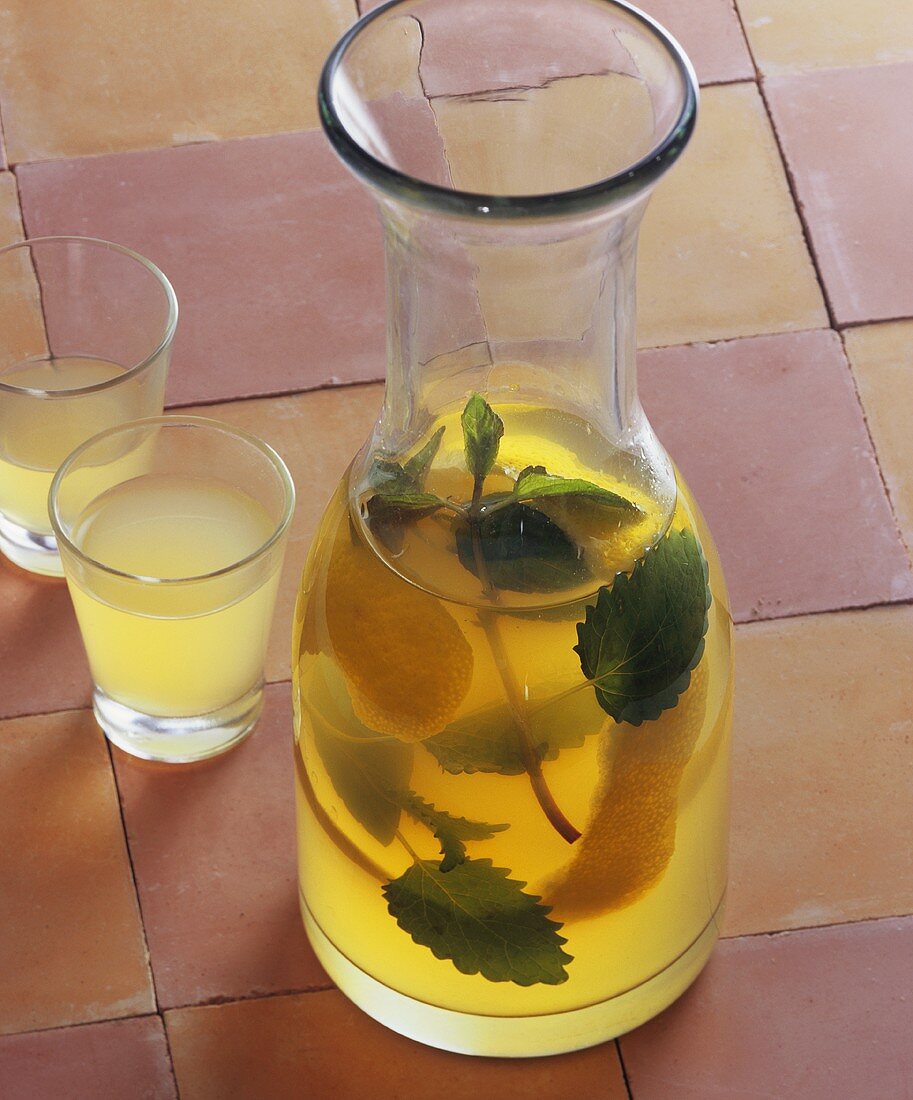 Home-made lemon balm and mint liqueur in carafe, glasses
