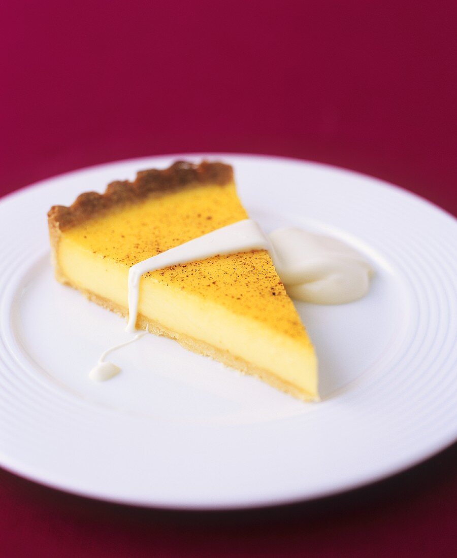 A piece of custard tart with custard sauce (UK)