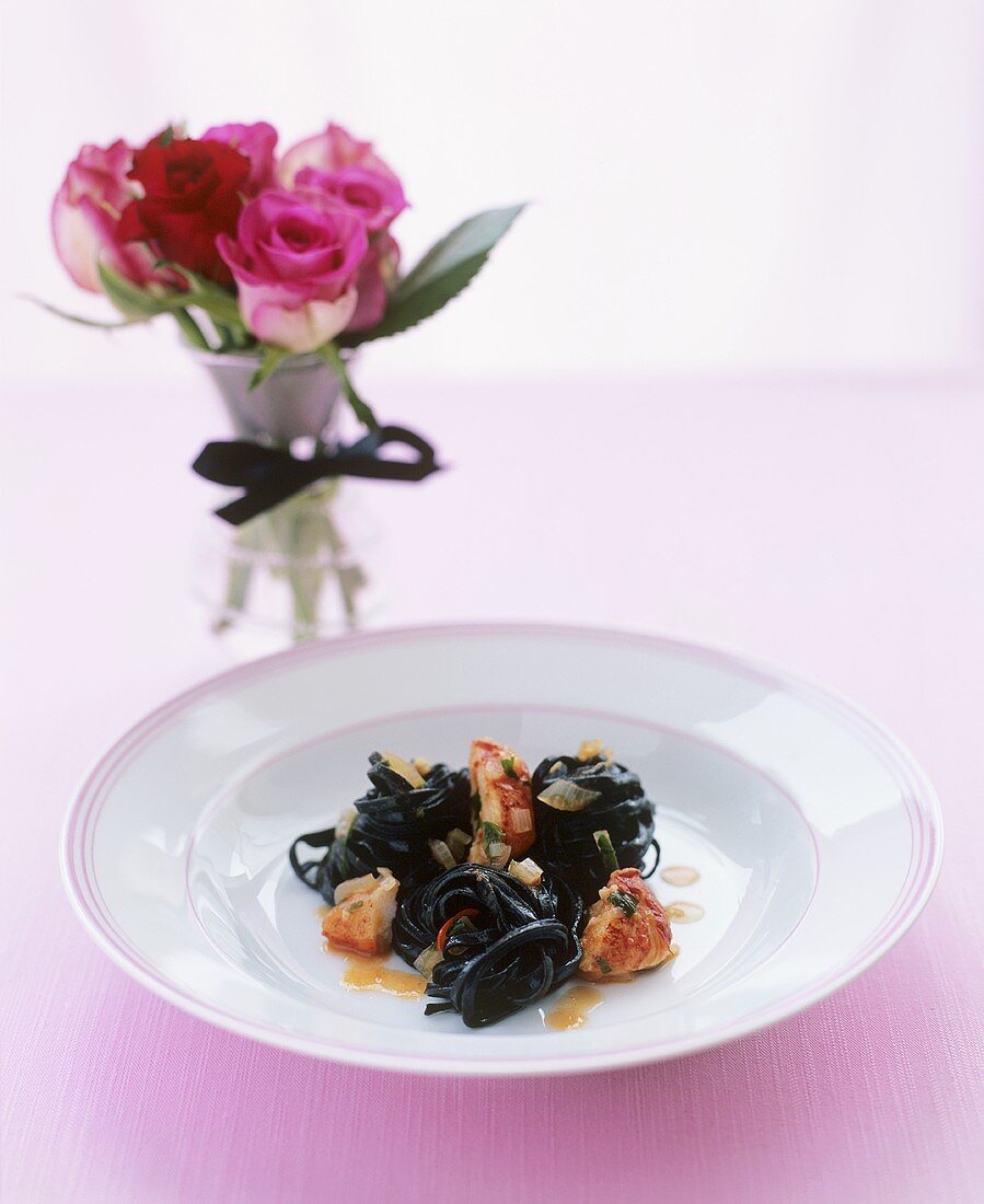 Black linguine with lobster, small vase of roses