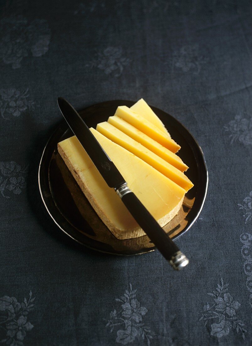 Hard cheese, partly sliced, with knife