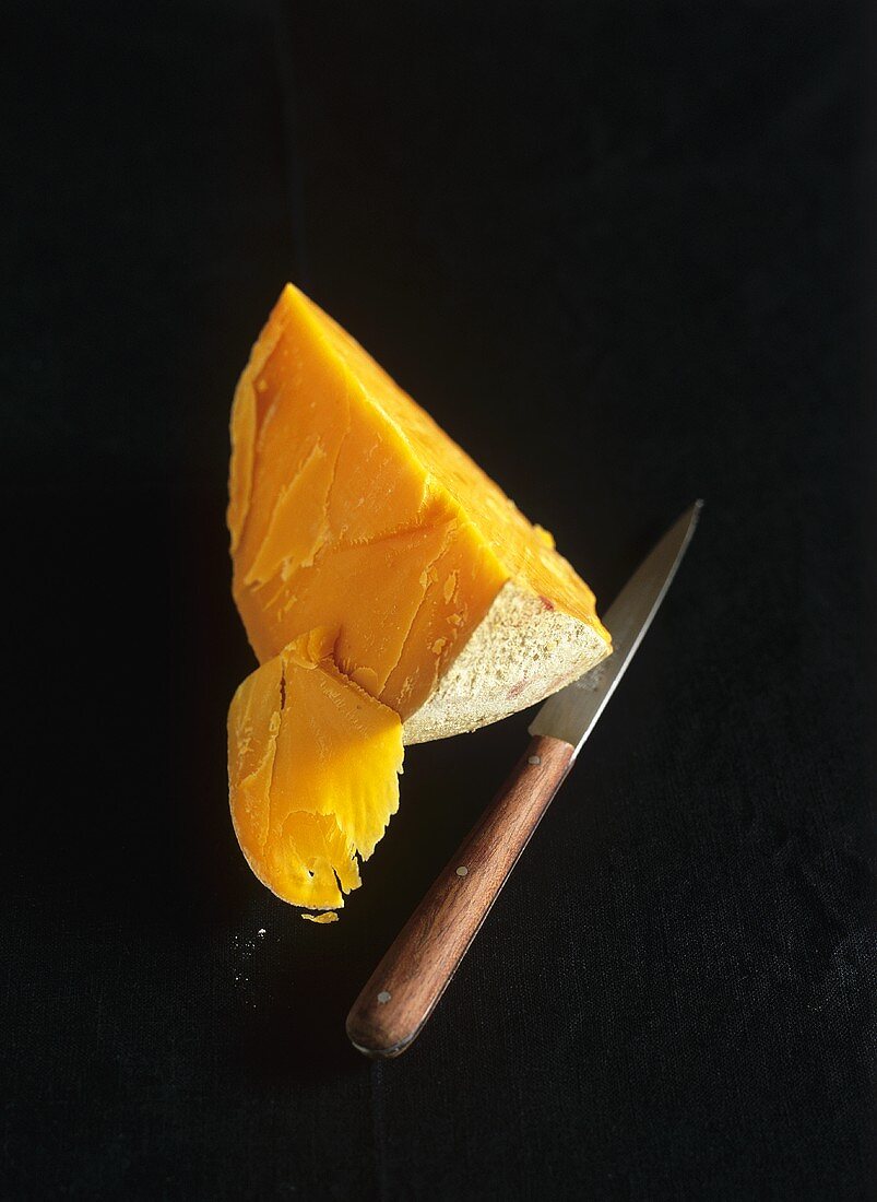 A piece of Mimolette with knife (French hard cheese)