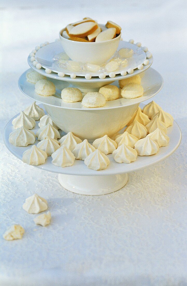 Small white cakes on cake stand composed of stacked crockery