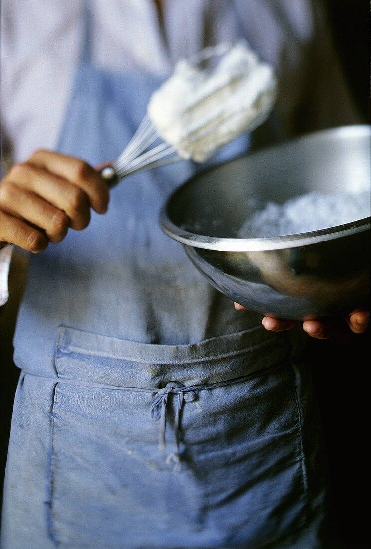 Man with a bowl of beaten egg white and whisk