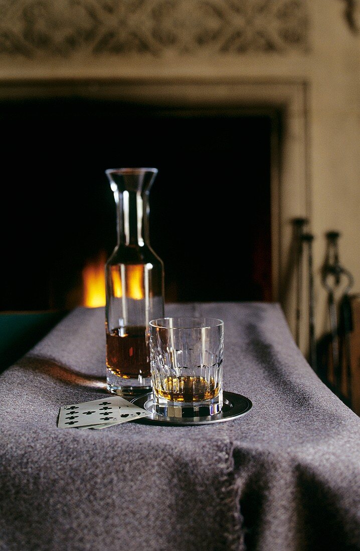 Branntwein in einer Karaffe und einem Glas vor dem Kamin