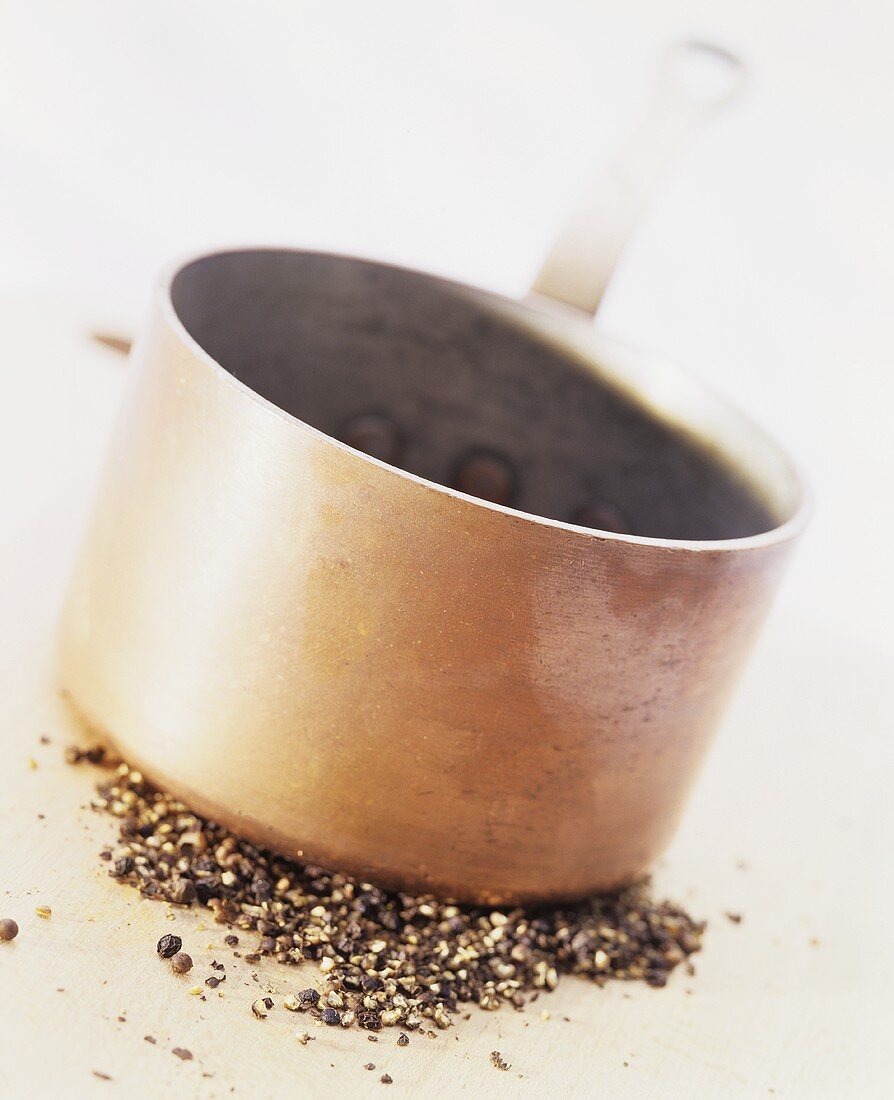 Peppercorns being crushed by a copper pan