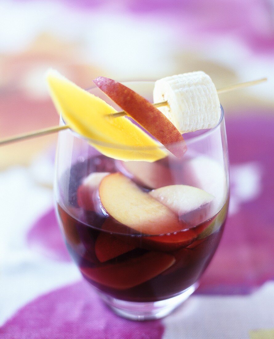 A glass of sangria with fruit skewer