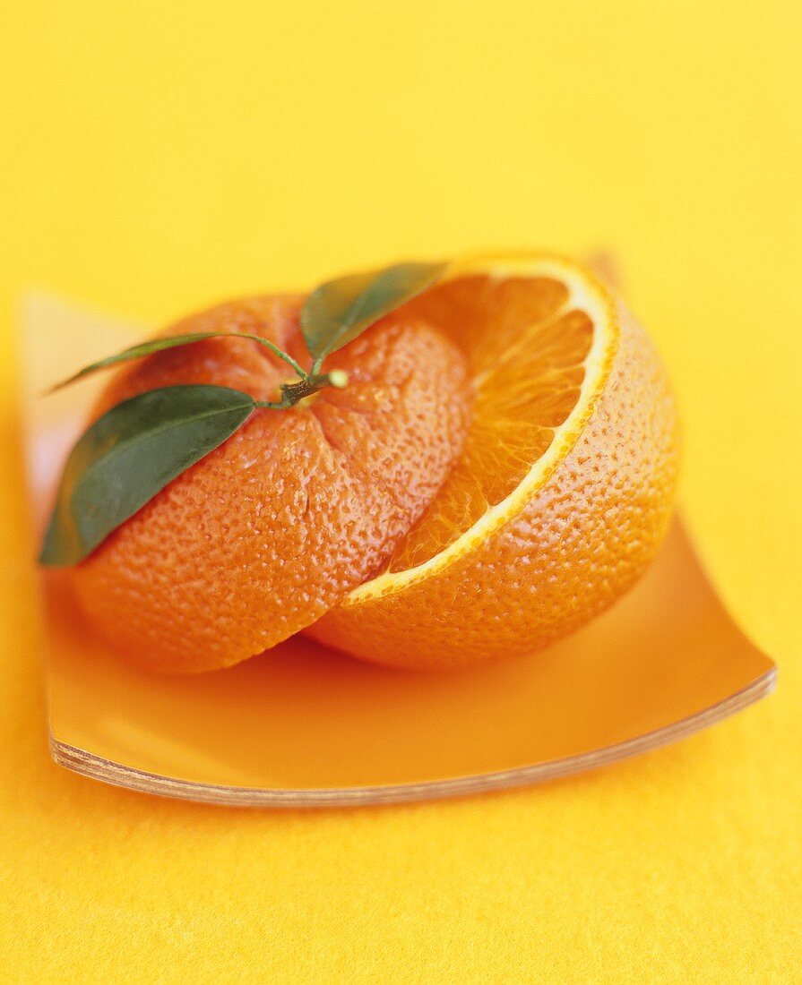 Halbierte Orange mit Blättern auf einem Teller
