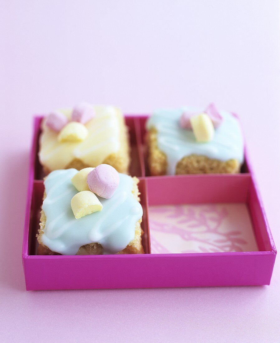 Minikuchen mit bunter Zuckerglasur in einer Geschenkschachtel