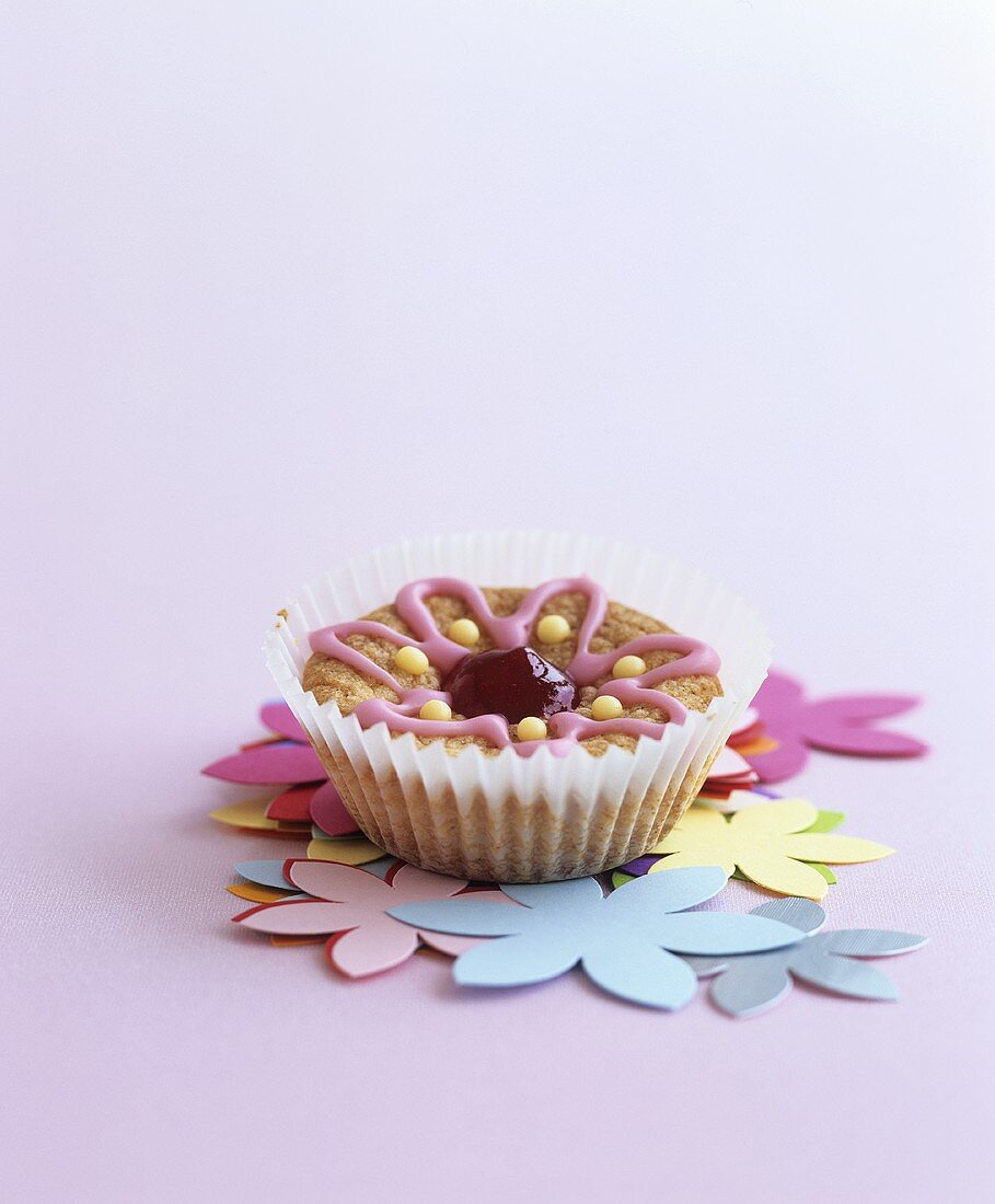 Muffin mit Blumen-Zuckerguss auf Papierblüten