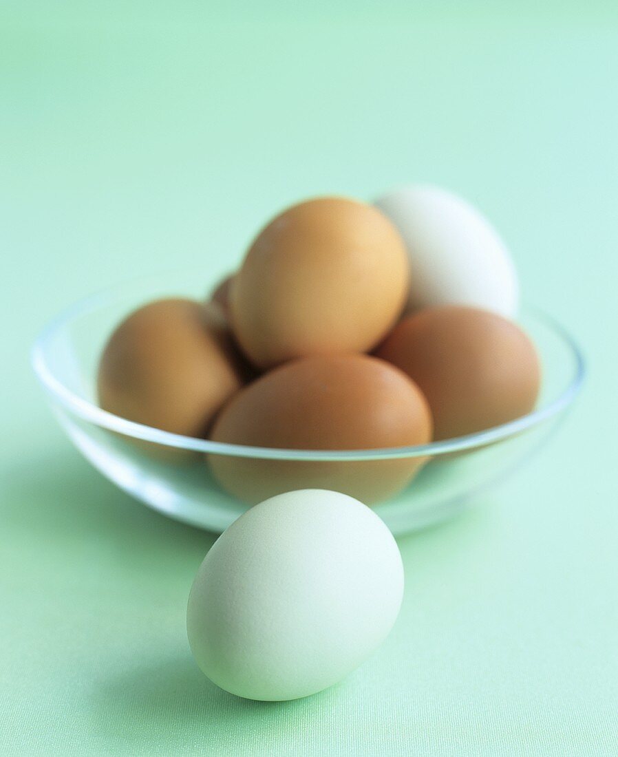 Brown and white eggs in and beside a glass bowl